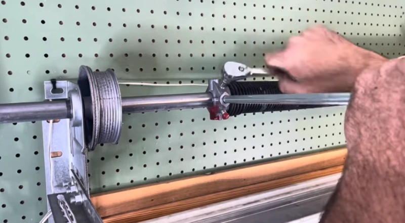 Technician replacing a broken torsion spring on a residential garage door